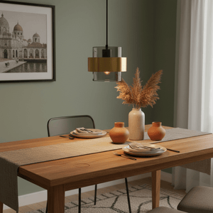 Astrid Gold Pendant Light hanging above a wooden dining table set with plates and decorative vases.