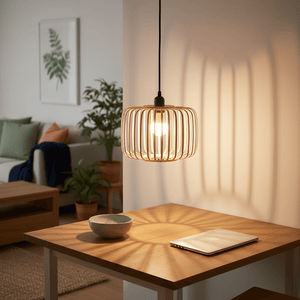 Haiku Bamboo & Metal Pendant Light hanging above a wooden table, casting soft shadows, with a bowl and laptop nearby.