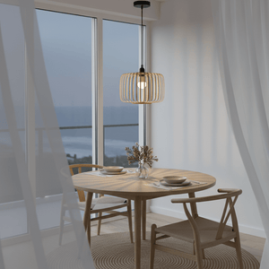 Haiku Bamboo & Metal Pendant Light hanging above a wooden dining table with ocean view.