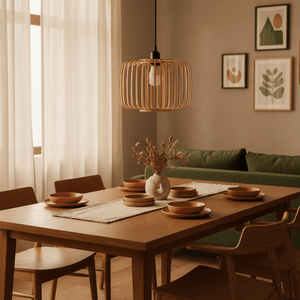 A bamboo and metal pendant light hangs above a wooden dining table set with plates and a vase of dried flowers.
