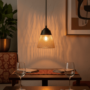 Stylish black and gold pendant light casting warm light over a dining table setting.