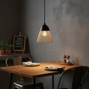 Billie black and gold pendant light hanging above a wooden dining table set for two.