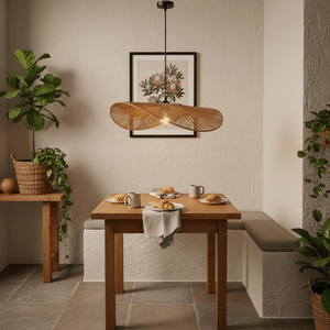 Aporia Natural Rattan Pendant light hanging above a wooden dining table set with pastries and mugs, surrounded by plants.