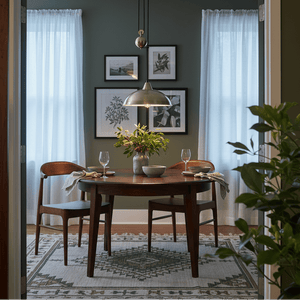 Stylish dining area featuring the Colchester Antique Brass Pulley Pendant Light above a wooden table with floral arrangement.