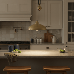 Antique brass pulley pendant light hanging over a kitchen island with limes and kitchenware.