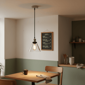 Satin chrome pendant light with clear glass shade hanging above a wooden dining table in a modern kitchen.