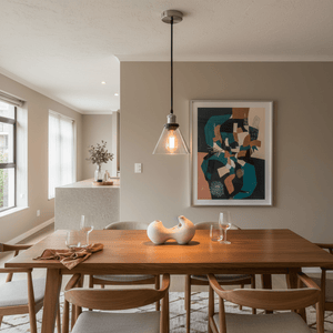 Satin chrome pendant light with clear glass shade hanging above a wooden dining table, featuring modern decor.