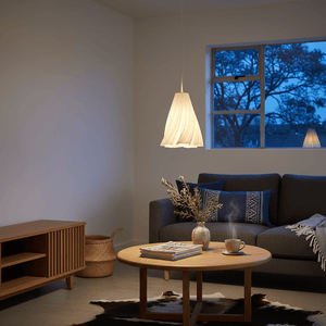 A stylish white pendant light hangs above a wooden coffee table in a cozy living room setting.