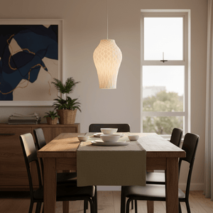 A white 3D printed pendant light hangs above a dining table set with plates and a table runner.