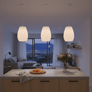 Three white 3D-printed pendant lights hang above a kitchen island, illuminating a modern living space.