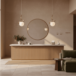 Gold infinity pendant lights hang above a modern reception desk with a round mirror and decorative plants.