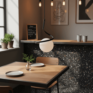 Black Infinity Pendant Light hanging above a wooden dining table with plates and a vase.