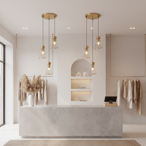 Sensu Cluster Gold Pendant Light hanging above a modern reception area with a marble counter and soft decor.