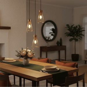 Three gold pendant lights hang above a wooden dining table set with plates and a vase of flowers.