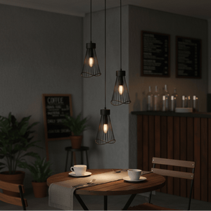 Three black pendant lights hang over a wooden dining table set with cups and a table runner, creating a cozy atmosphere.