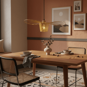 Satin-gold pendant light hanging above a wooden dining table set with dishes and decor.