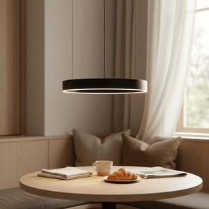 A black LED pendant light hangs above a round wooden table with a cup, croissant, and folded napkins.