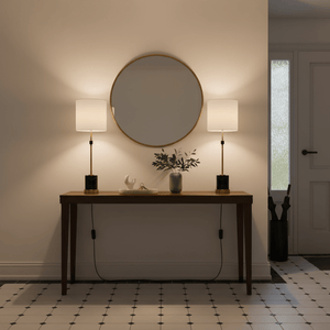 Two elegant table lamps with white shades on a wooden console table, reflecting warm light in a stylish entryway.