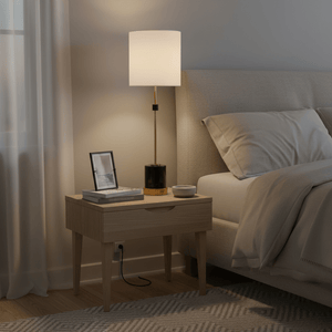 Stylish black and gold marble table lamp on a bedside table, with books and a photo frame nearby.