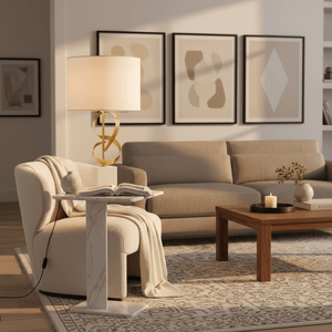 Elegant marble and gold table lamp on a stylish side table next to a cozy armchair, with a book and blanket.