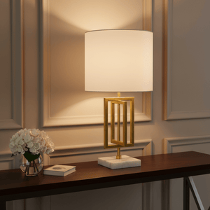Chopin Gold & Marble Table Lamp on a wooden sideboard with flowers and a book.