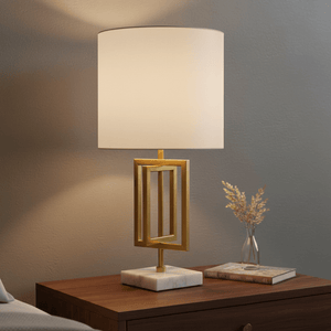 Chopin Gold & Marble Table Lamp on a wooden bedside table, with a decorative vase and books nearby.