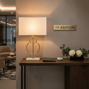 Beethoven Gold & Marble Table Lamp on a console table with decorative flowers and a notebook.
