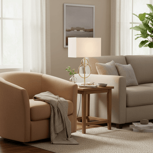 Beethoven Gold & Marble Table Lamp on a side table next to a cozy armchair in a stylish living room setting.