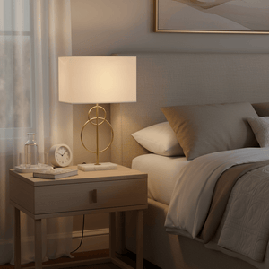 Beethoven Gold & Marble Table Lamp on a bedside table with a clock and water bottle.