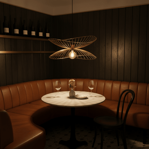 Satin gold twin pendant light above a round marble table in a cozy dining nook with brown leather seating.