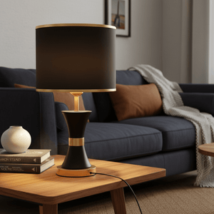 Efron Black & Gold Table Lamp on a wooden side table beside a cozy couch, with books and a vase.