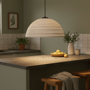 Antique white rattan pendant light hanging over a kitchen island with lemons and greenery.