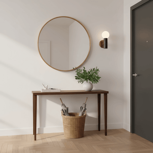 Stylish indoor scene featuring a round mirror above a console table with a marble wall light, plants, and a basket.