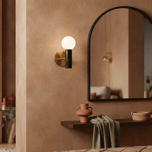 Ollie Black Marble Wall Light mounted beside a mirror in a warm-toned room, with decorative items on a shelf.