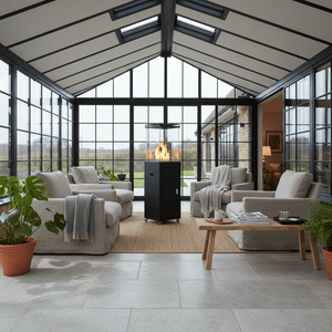 A stylish black fire cube heater stands in a bright, modern sunroom surrounded by cozy seating.