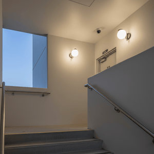 Outdoor wall light illuminating a stairwell, featuring a modern design with an opal dome.