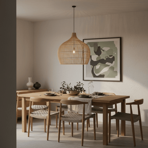 Woven bamboo rattan pendant light hanging over a wooden dining table set with plates and decor.