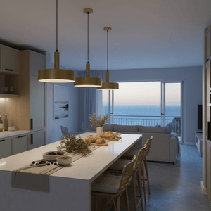 Three Sombre Gold Pendants hang above a modern kitchen island, illuminating a serene dining space with ocean views.
