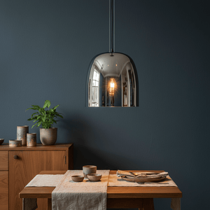 Smoke-tinted dome pendant light hanging above a wooden dining table set with dishes and a plant.