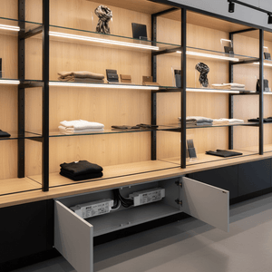Open cabinet under glass shelving unit reveals two white LED power supplies with black cables