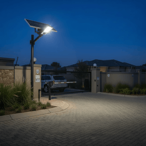 Solar street light illuminating a gated entrance at night, showcasing its solar panel and bright light.