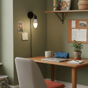 A cozy workspace featuring a wall-mounted light with a frosted LED bulb, a wooden desk, and decorative items.