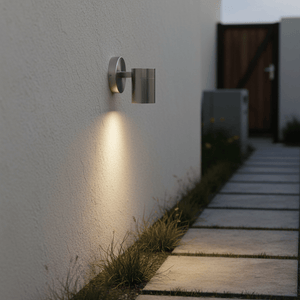 Modern outdoor wall light illuminating a stone pathway beside a textured wall, enhancing visibility.