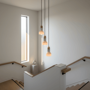 Three marble and gold pendant lights hanging in a modern stairwell, illuminating the space elegantly.