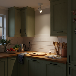A modern white ceiling spotlight illuminating a kitchen countertop with fresh vegetables and utensils.
