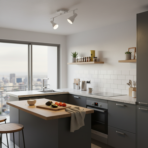 A modern kitchen featuring a matt white two-head spotlight illuminating a wooden countertop with fresh produce.