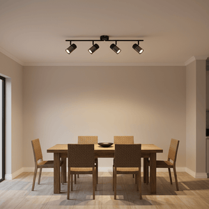 Black 4-light spotlight with moveable arms installed above a wooden dining table and chairs.