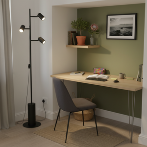 Modern black metal floor lamp with three adjustable heads beside a desk in a cozy workspace.