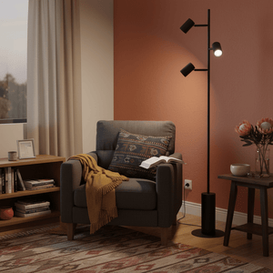 Modern black metal floor lamp with three adjustable heads beside a cozy armchair and side table.