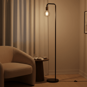 Sleek black floor lamp beside a cozy armchair, illuminating a warm living space with soft light.